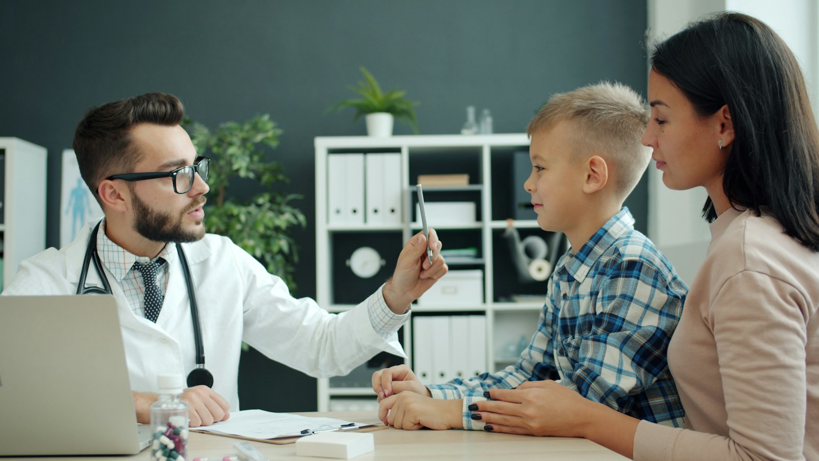 A doctor seeing a boy with his mother beside him