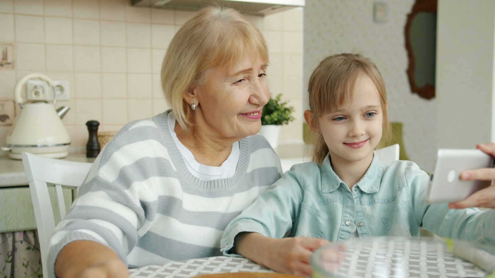 A grandmother and her granddaughter looking at a phone together